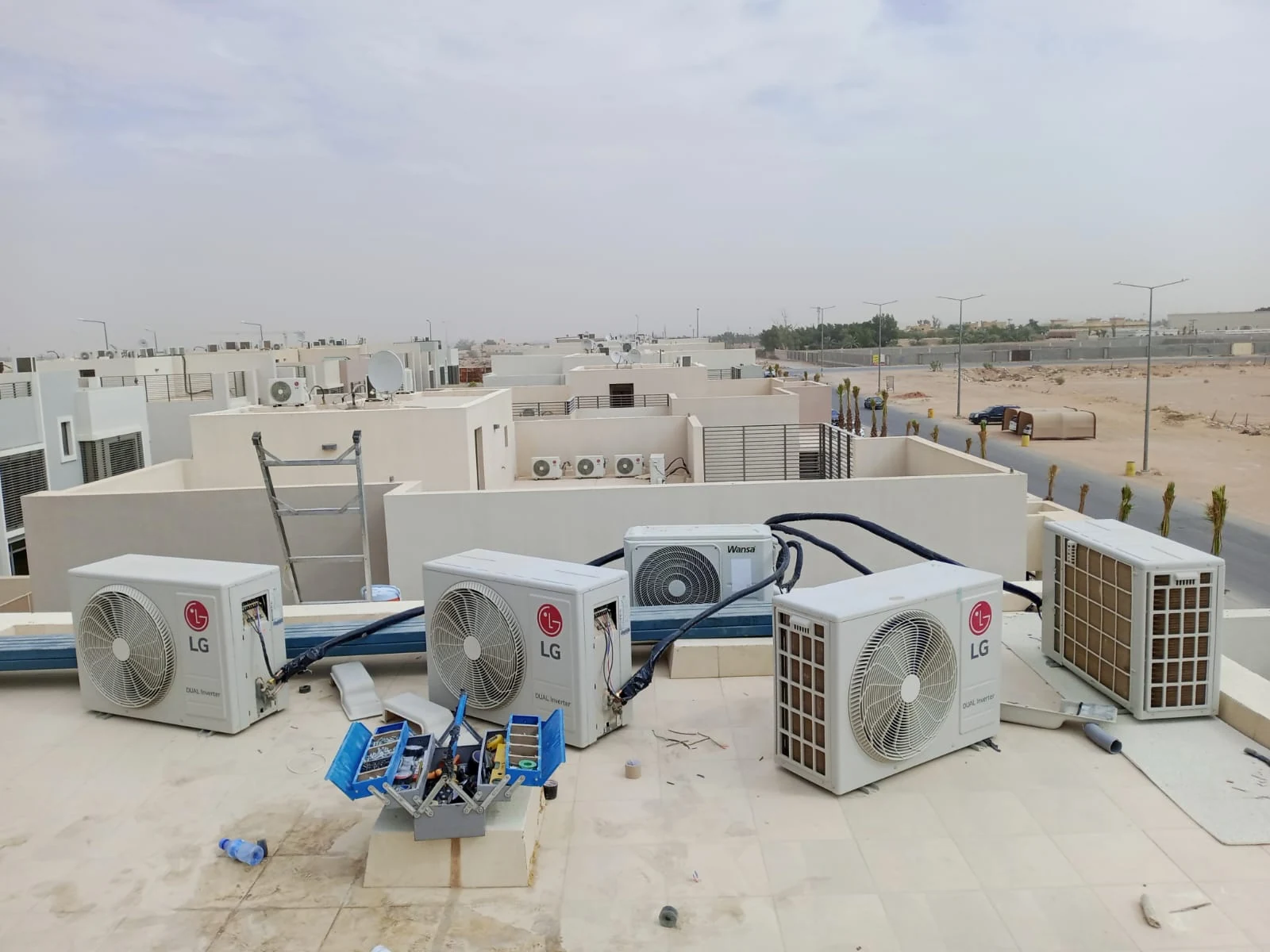 خدمات المكيفات بالرياض: وحدات تكييف خارجية وتمديدات وصندوق أدوات على أرضية سطح